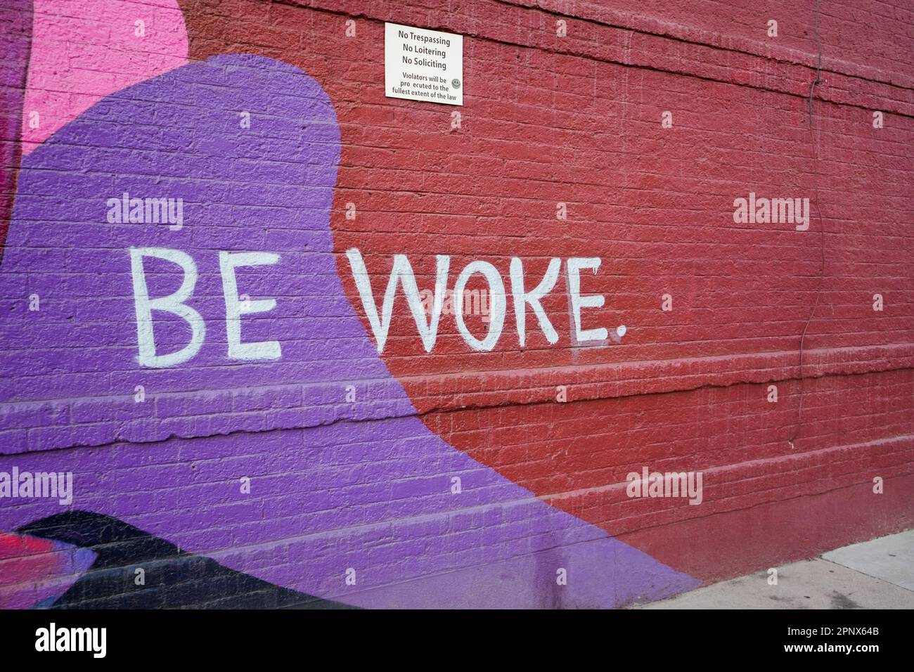 Be woke sign on a brick wall Stock Photo