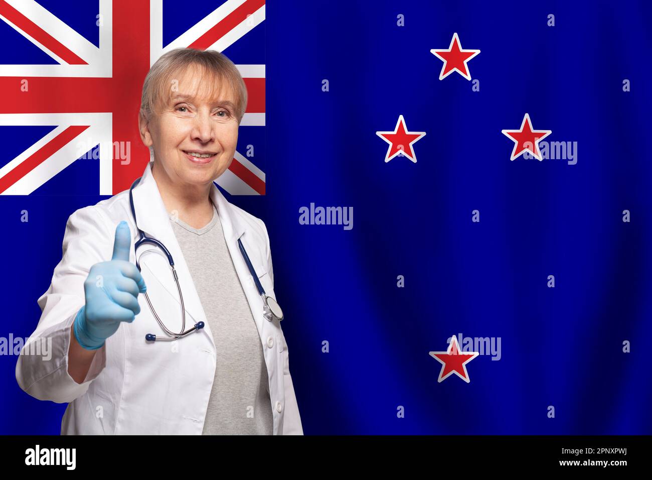 New Zealand smiling mature doctor woman holding stethoscope on flag of New Zealand background