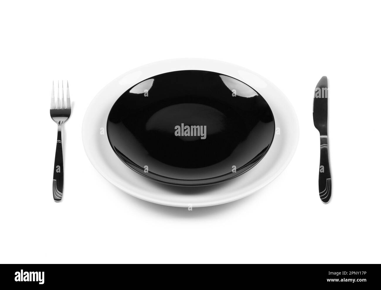 Two stacked black and white plates with fork and knife, overhead side