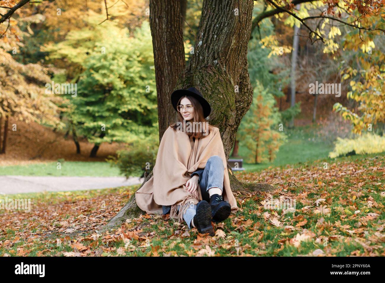 brown-haired woman in a black hat and poncho in the park Stock Photo