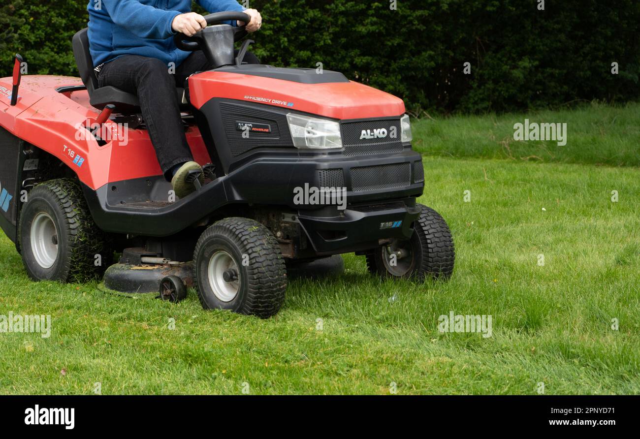 A man cuts grass with an ALKO ride on lawn mower. Stock Photo