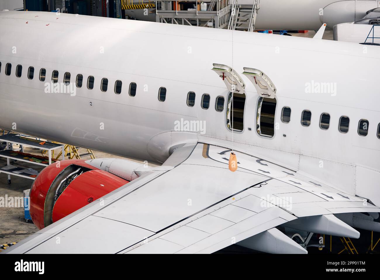 Commercial airplane under heavy maintenance. Side view of plane fuselage with emergency exits and wing. Stock Photo