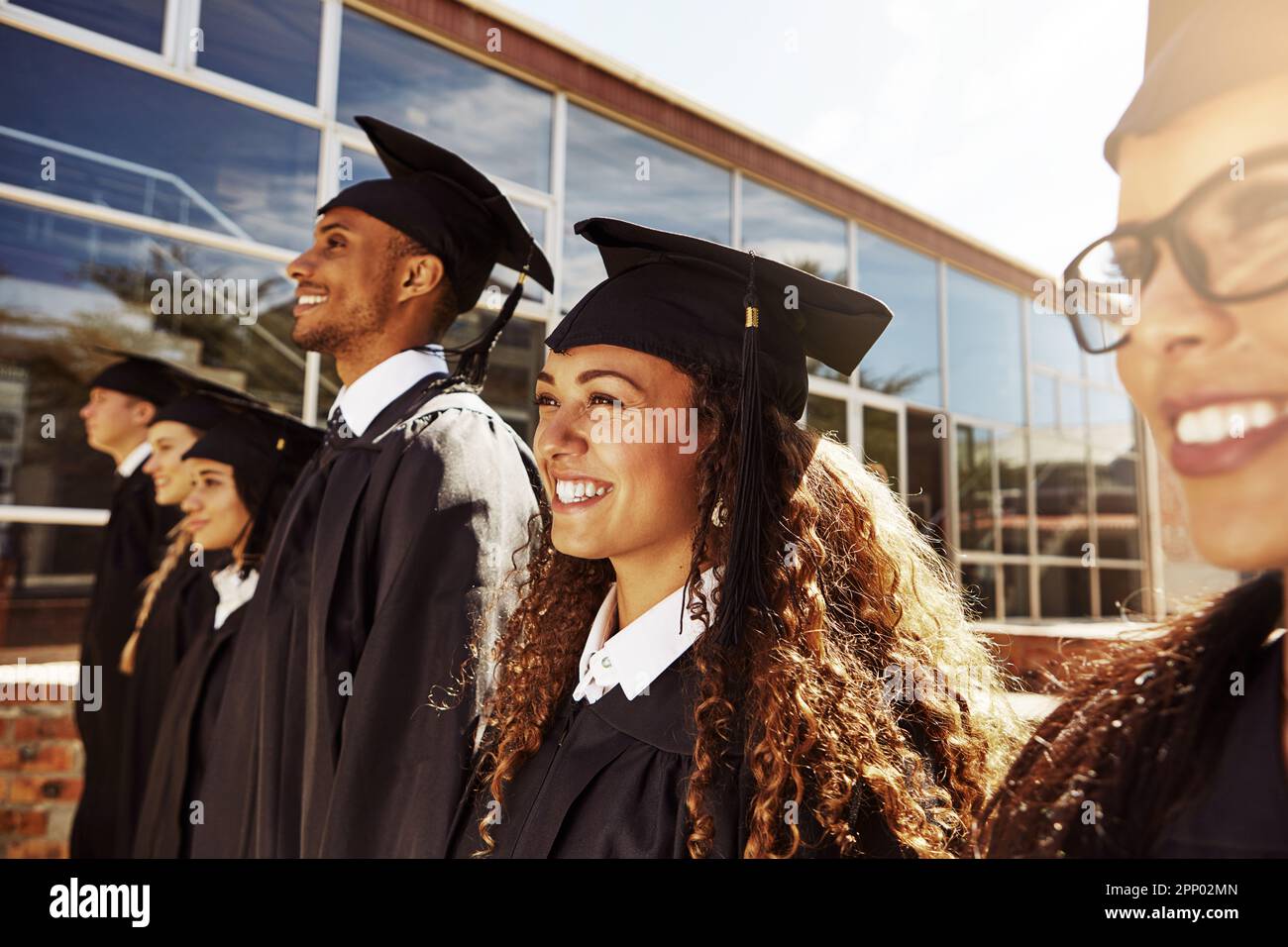 Staring towards a bright future. a group of smiling university students outside on graduation day. Stock Photo