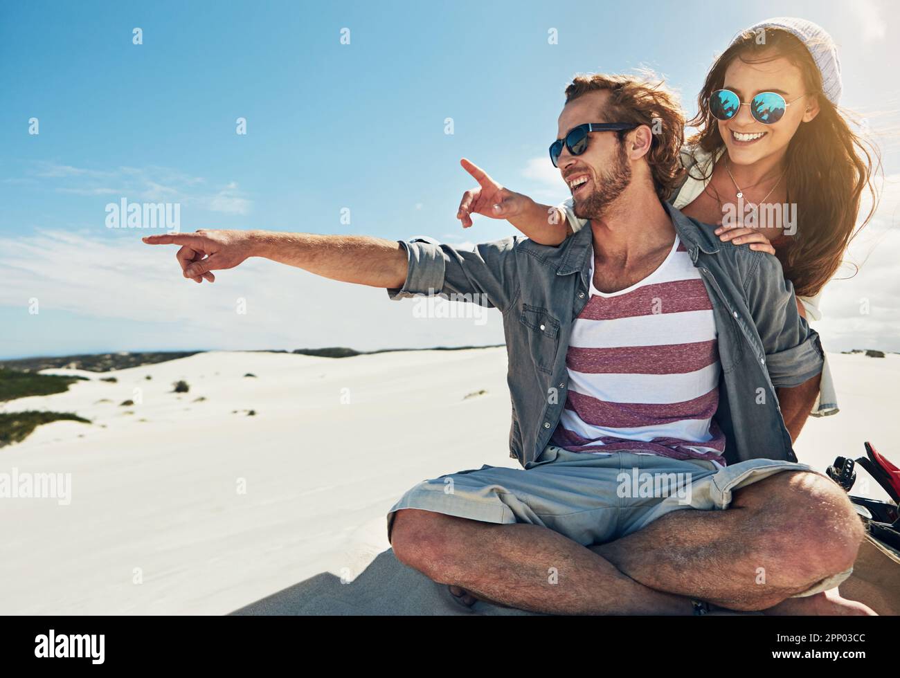 Lets ride that dune. a young couple sandboarding in the desert. Stock Photo