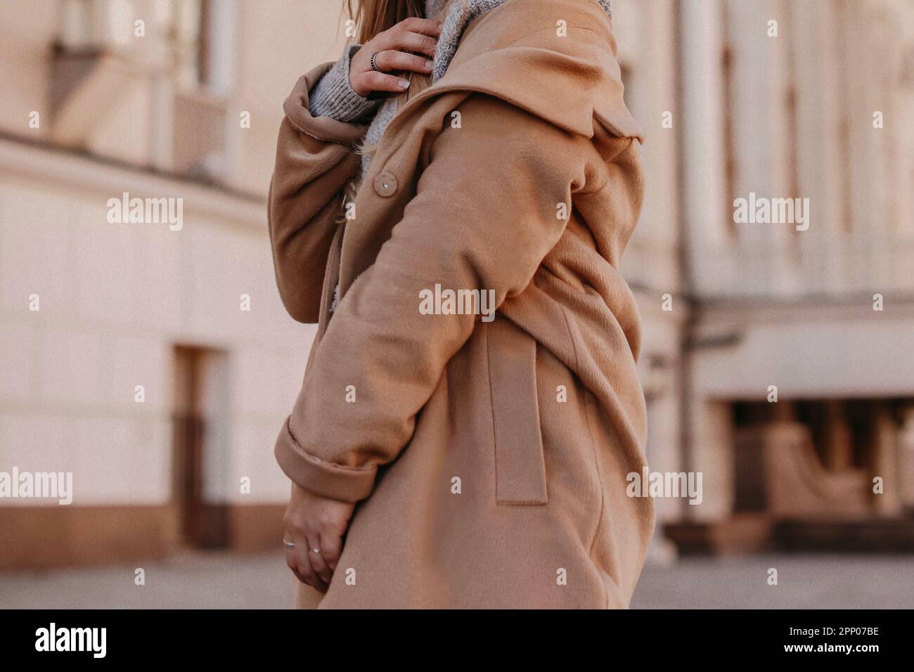 Outdoor fashion portrait of stylish young woman having fun, emotional face  , laughing, looking at camera. Urban city street style. Long jeans coat and  orange hoodie. Spring or fall outfit. Stock Photo