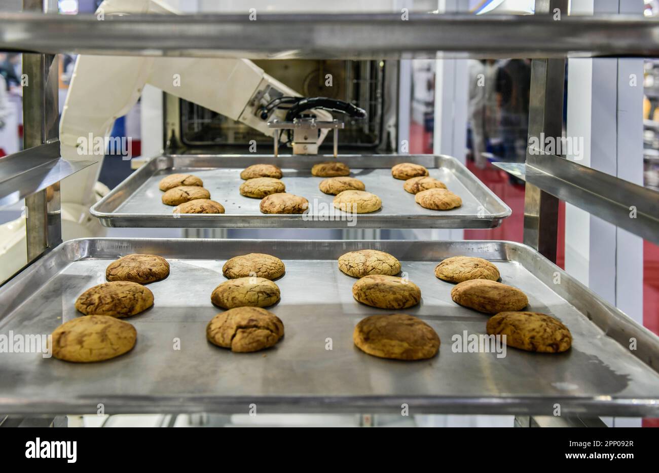 Robot arm preparing cookies for the oven in production line factory, industrial food production. Stock Photo