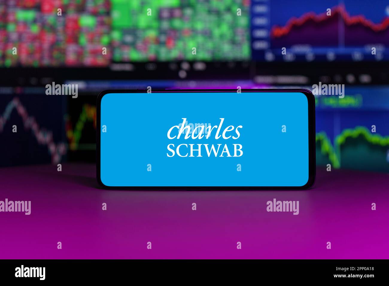 Charles Schwab stock market index in front of stock market charts