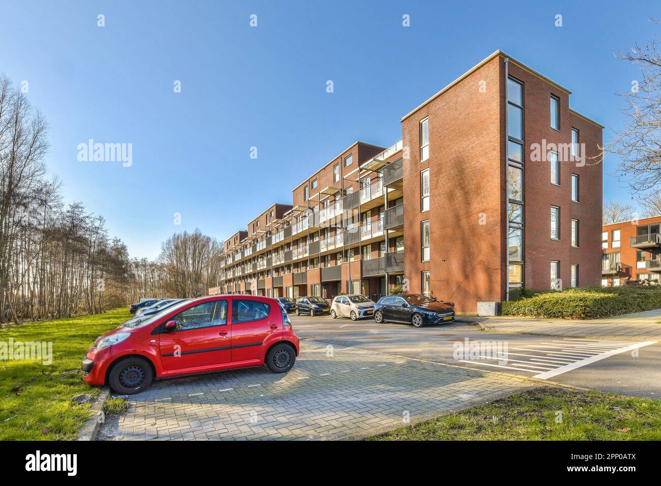 a red car parked in front of a large brick apartment building on a ...