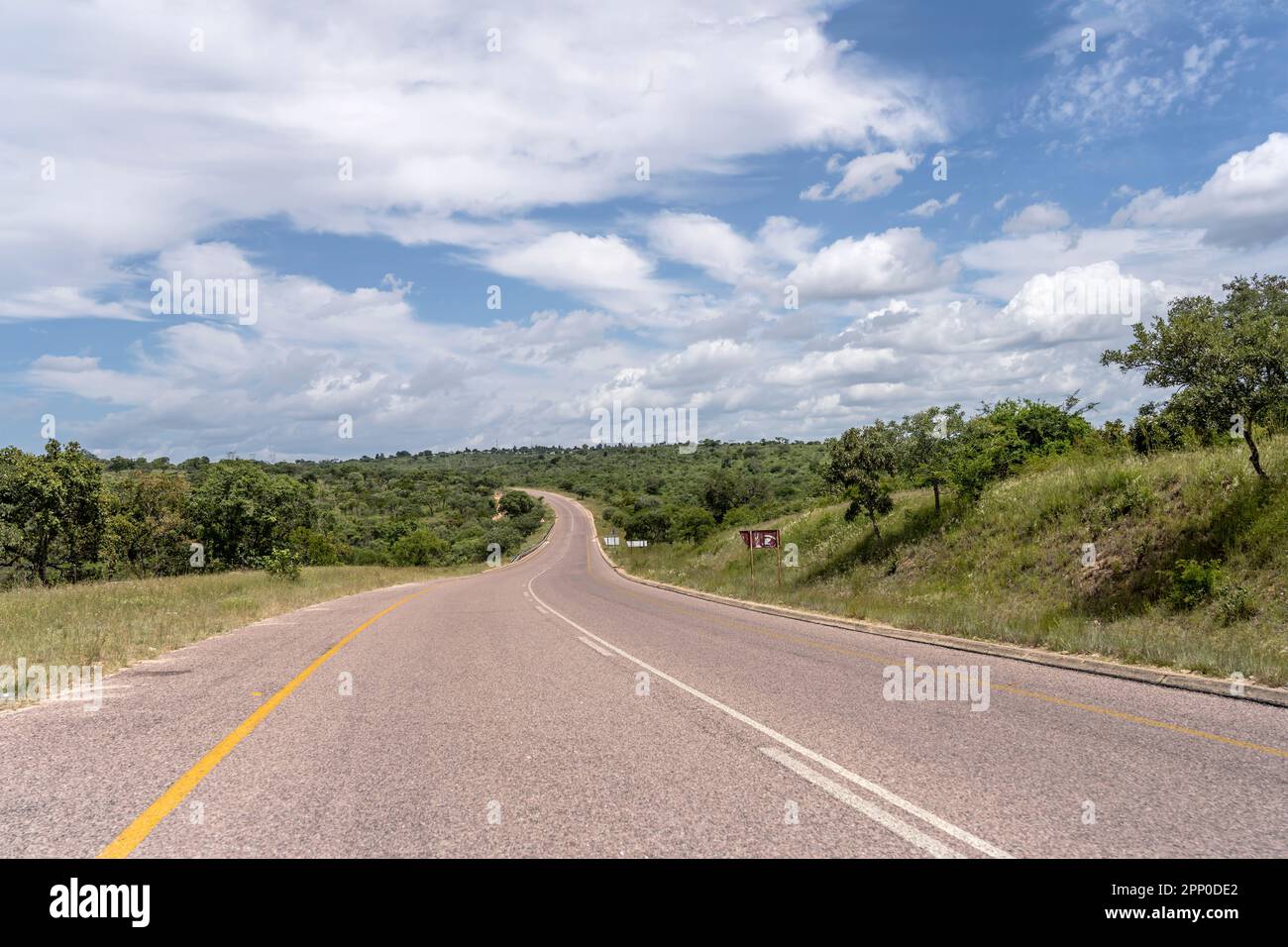 landscape with  R40 road bending in hilly countryside near Timbavati, shot in bright summer light , Mpumalanga, South Africa Stock Photo