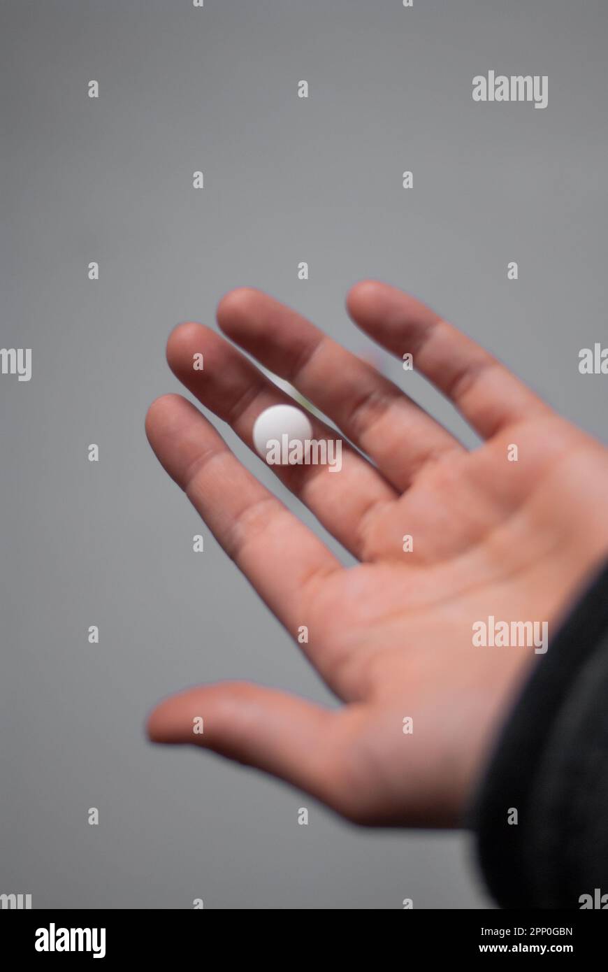 View of hand with white pill on the white background Stock Photo