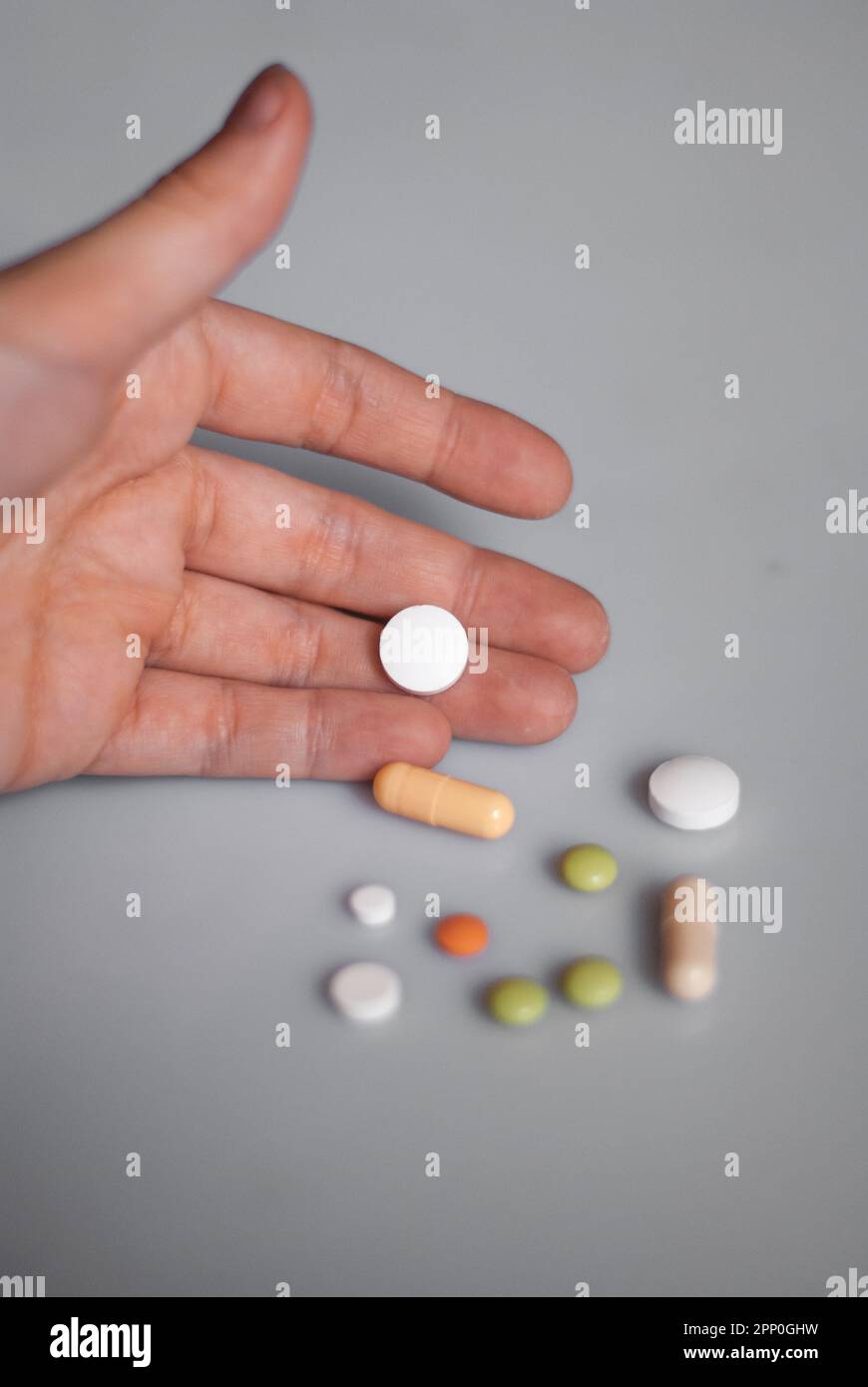 View of white pill on a hand near pills on the white background Stock Photo