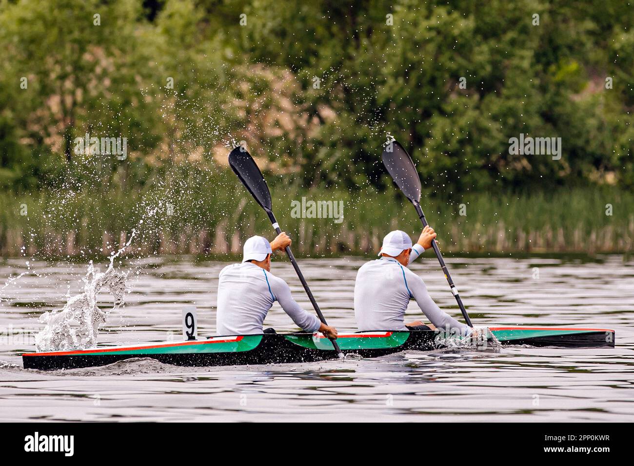 side view male kayakers on kayak double in kayaking competition race, water splashes from paddles Stock Photo
