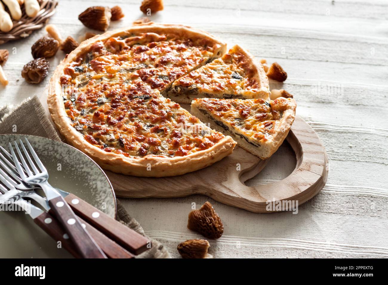 Quiche – open tart pie with morel mushrooms, onion and mozzarella cheese on wooden cutting board Stock Photo