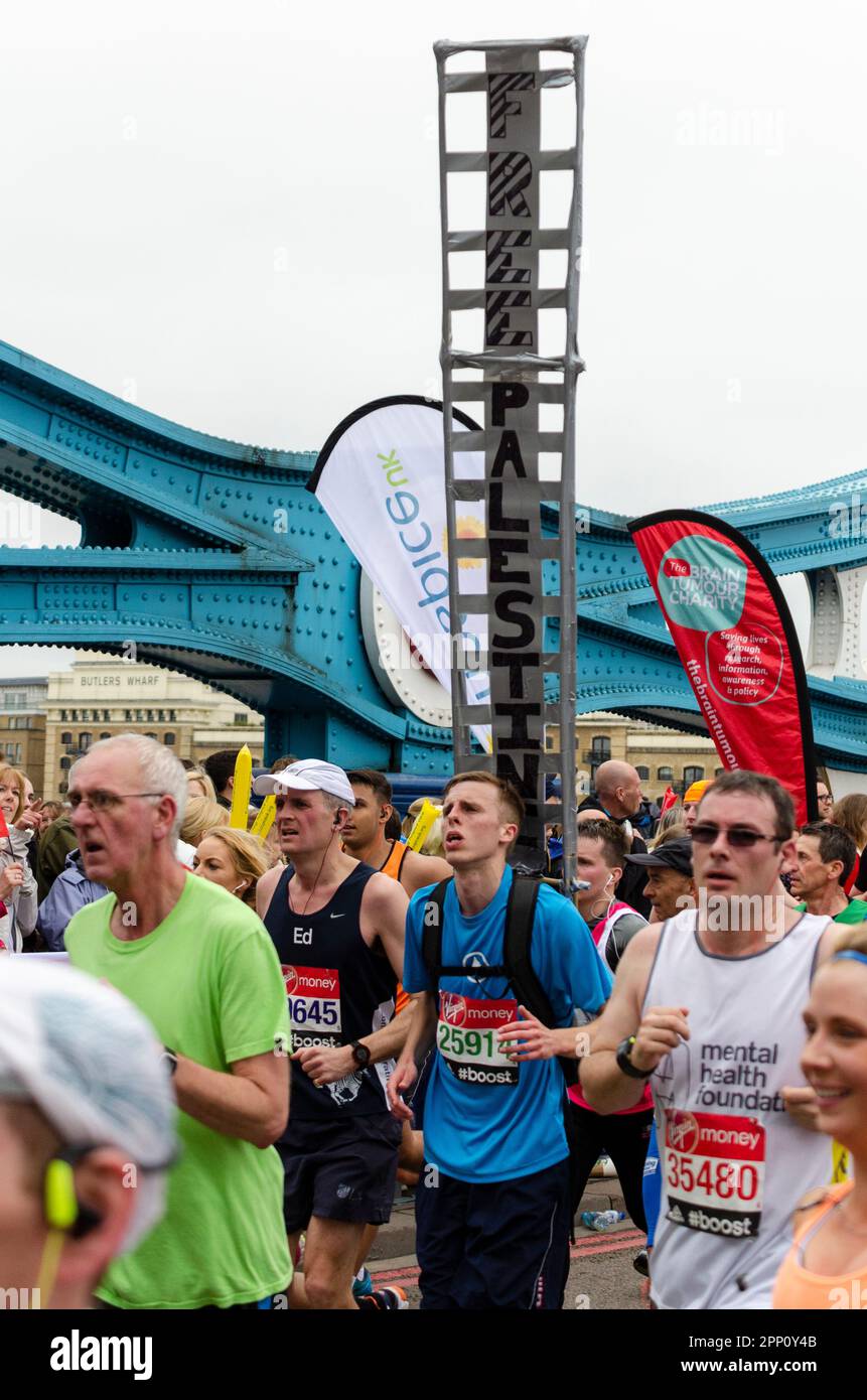 Runner with large Free Palestine protest placard competing in the Virgin Money London Marathon 2015 crossing Tower Bridge, UK. Protester running Stock Photo