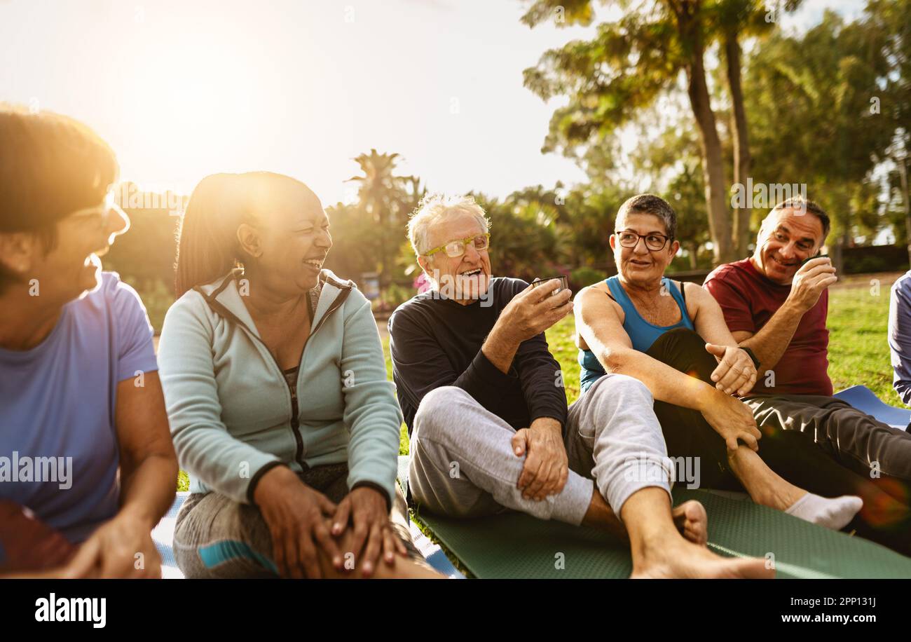 Happy multiracial senior friends drinking a tea after workout activities in a park Stock Photo