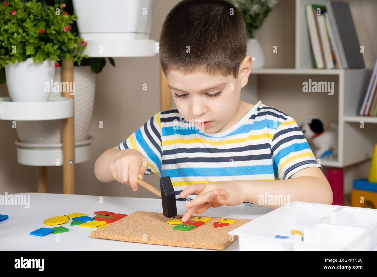 A preschool child plays with a mosaic, builds figures on a board