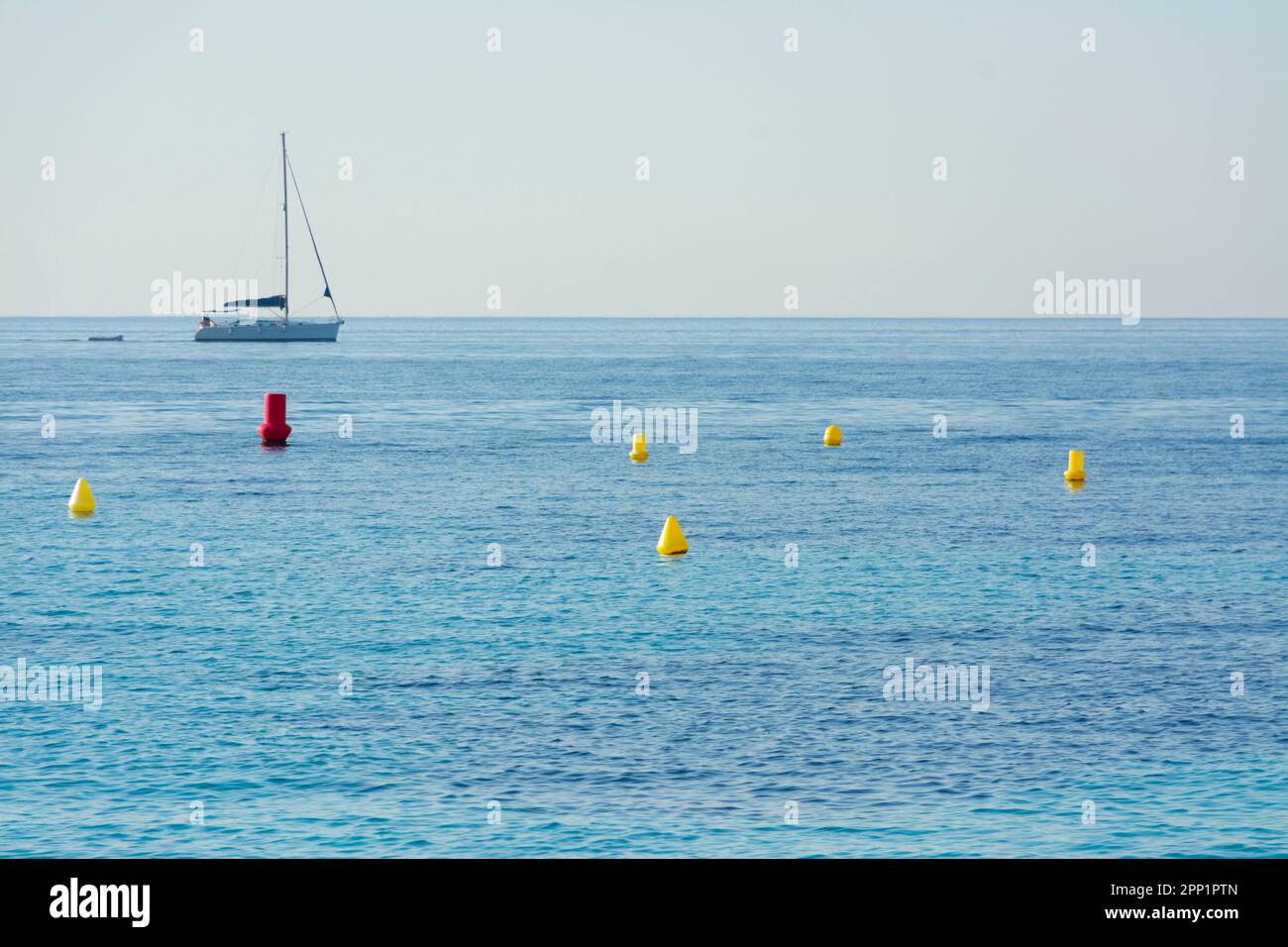 Sailboat sailing off the coast of Ses Illetes, in Mallorca, with buoys in the water Stock Photo