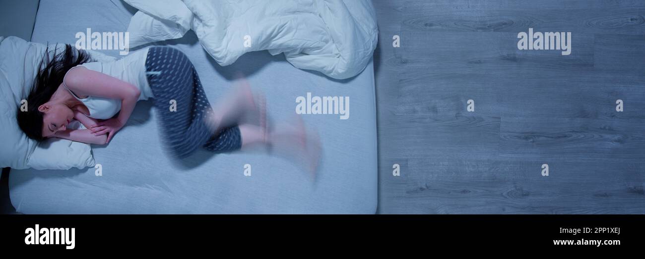 Woman With RLS Restless Legs Syndrome. Sleeping In Bed Stock Photo