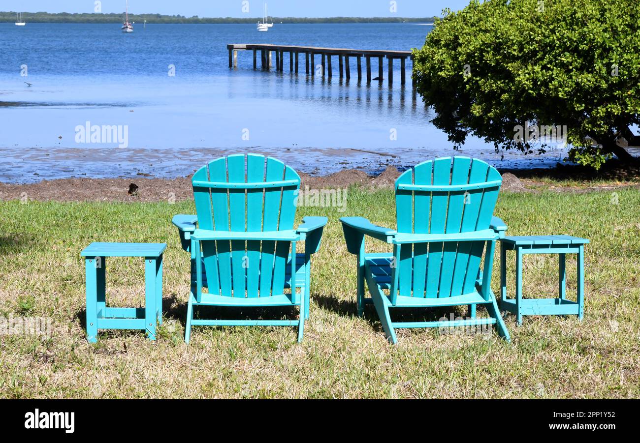 empty Adirondack lawn chairs along the ocean shore Stock Photo