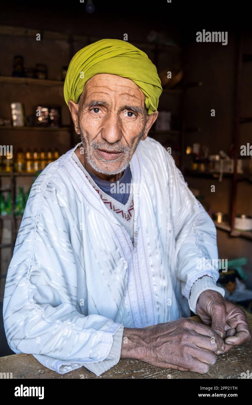 Portrait of berber man dressed in traditional berber clothes in his small shop. Stock Photo
