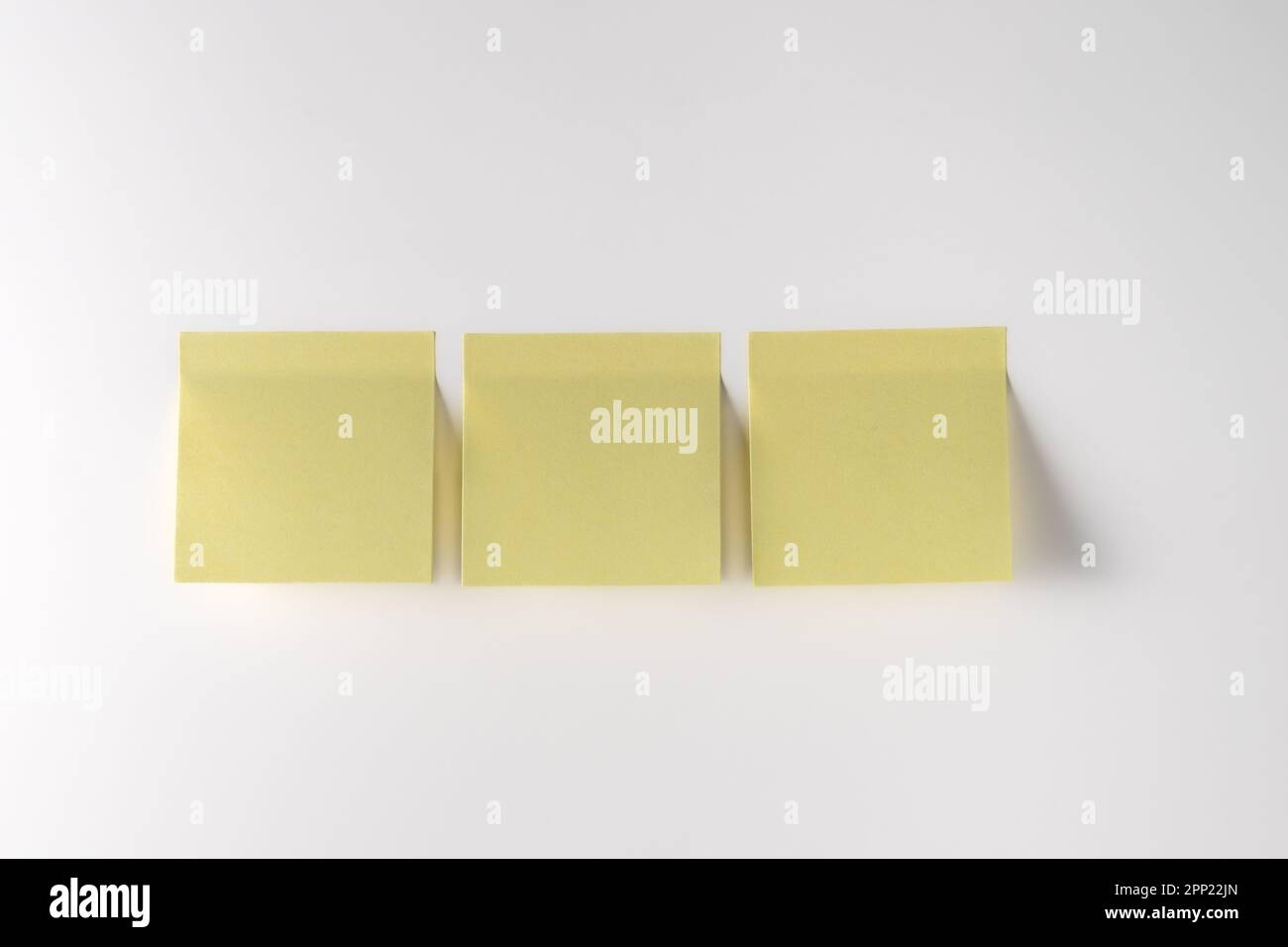 Yellow note paper on white background. Copy space. Close up. Stock Photo