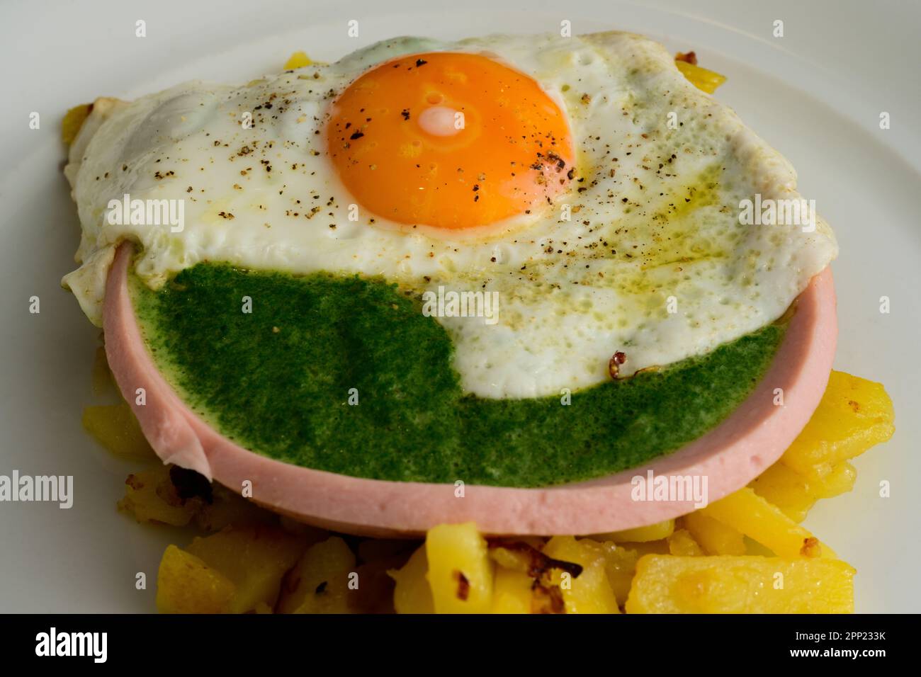 Fried Egg on Spinach in a Sausage Bowl and Roasted Potatoes Austrian Style Stock Photo