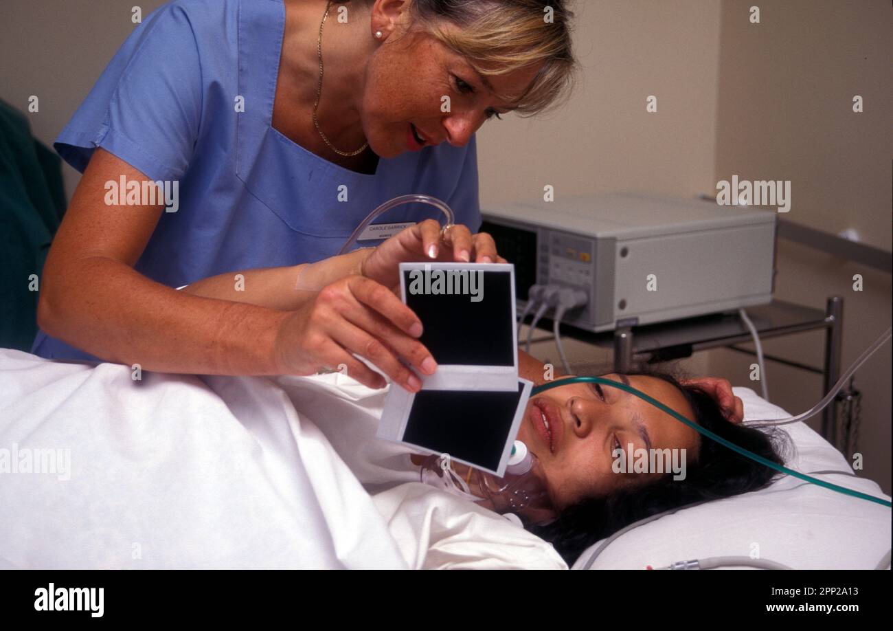 midwife showing hispanic woman in recovery photographs of her baby born by cesarian section Stock Photo