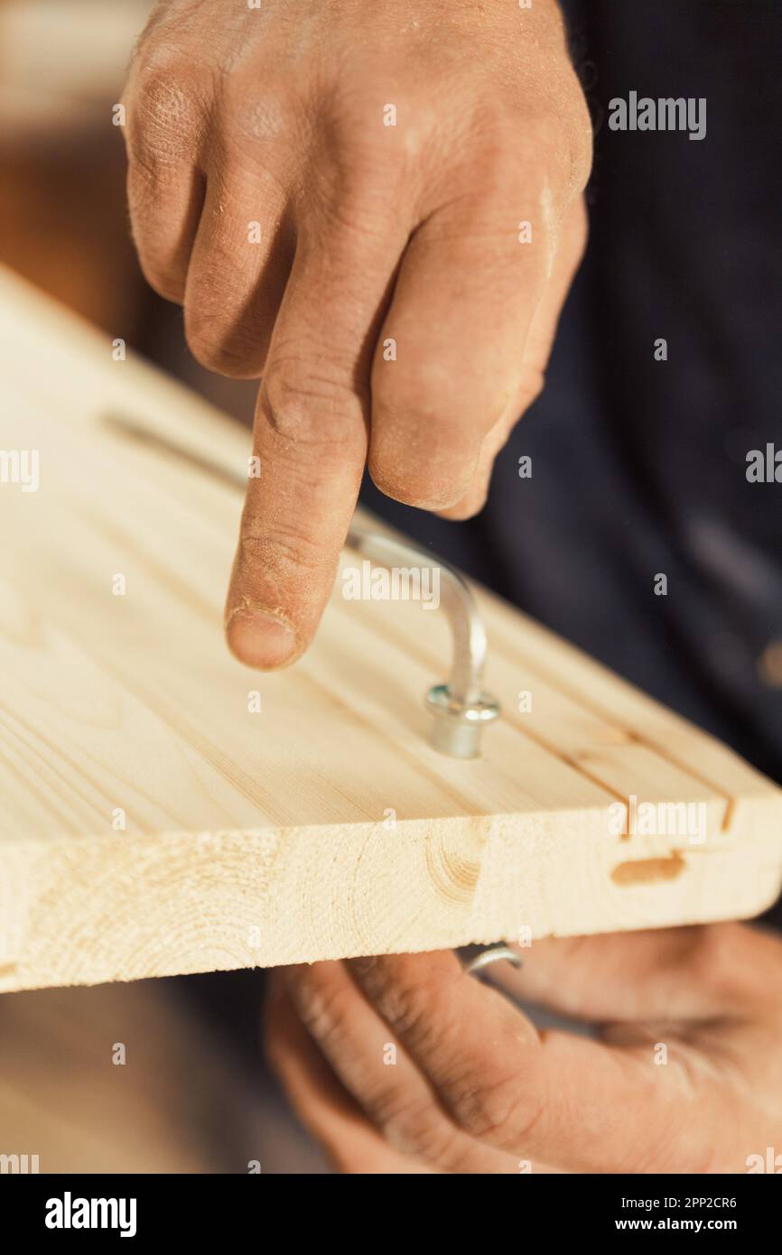 The carpenter screws and secures a wooden board using an Allen key ...
