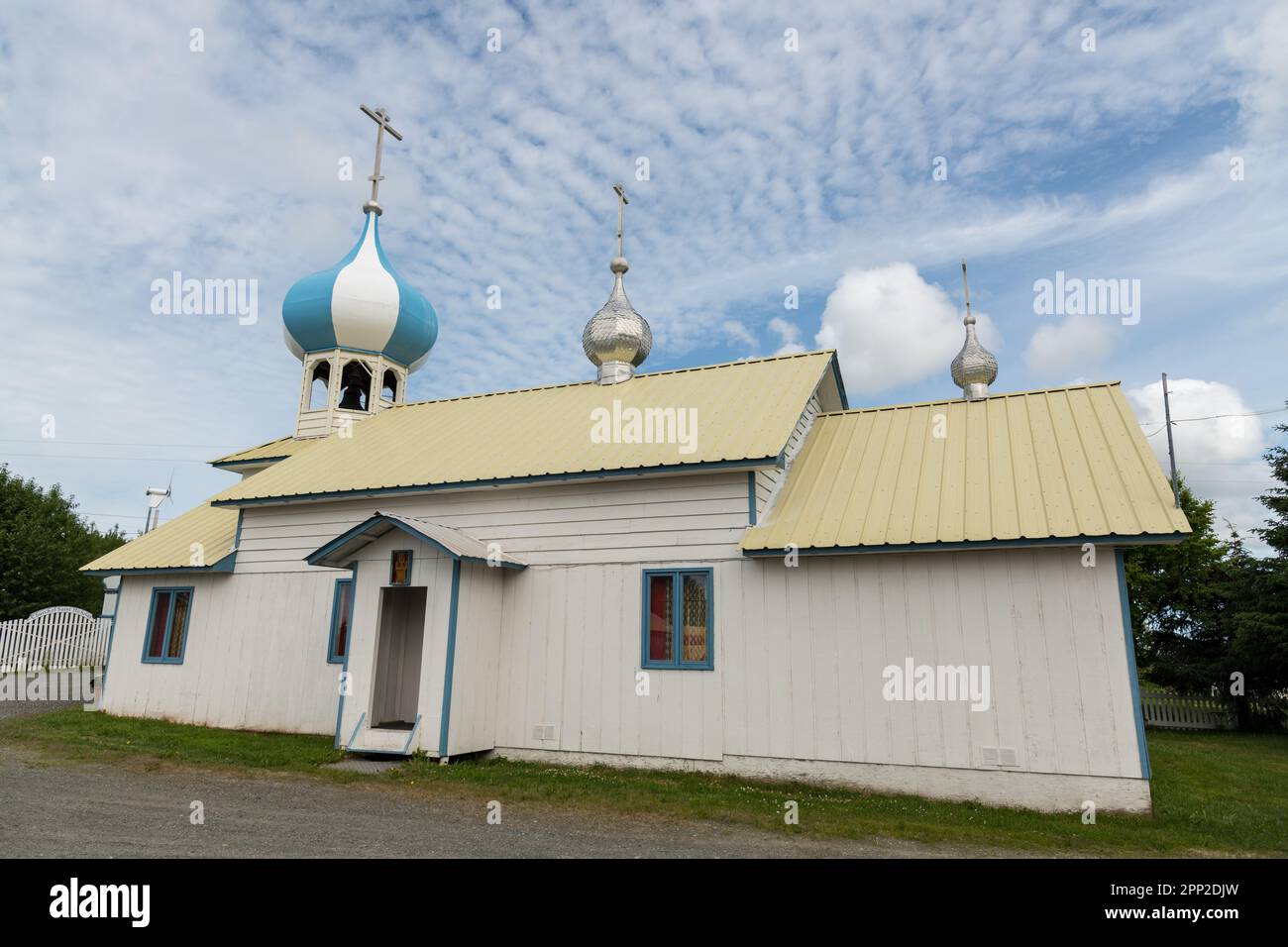 The blue and white striped onion dome and ornate entrance of Saint Nicholas Russian Orthodox Church in Nikolaevsk, Alaska. The wooden church was built by Russian migrants of the Old Believers sect, who fled religious persecution in the 17th-century Stock Photo