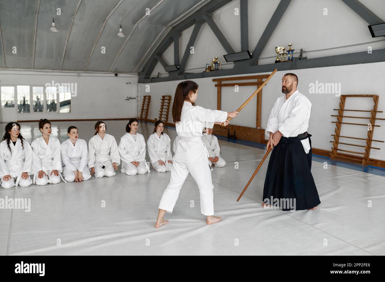 Girl and aikido master fighting with wooden sword during martial arts class Stock Photo