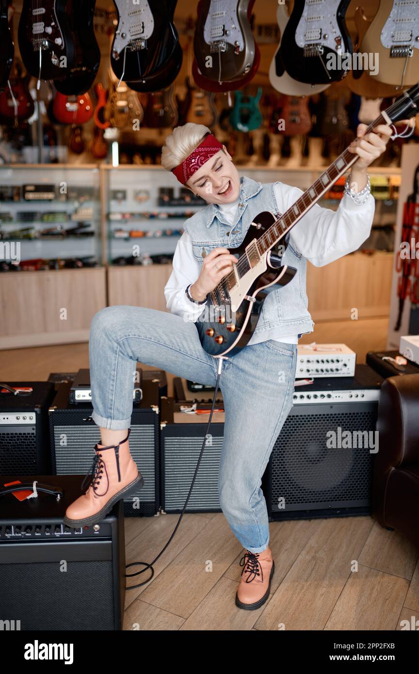 Alamy Rocker Woman rocker playing guitar connected to amplifier over shop store ...