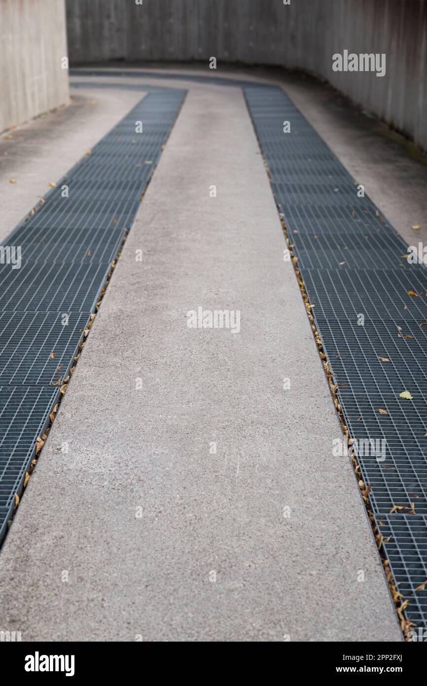 Driveway with metal grates to an underground parking garage, turns left. Shallow depth of field, focused on the front. Stock Photo