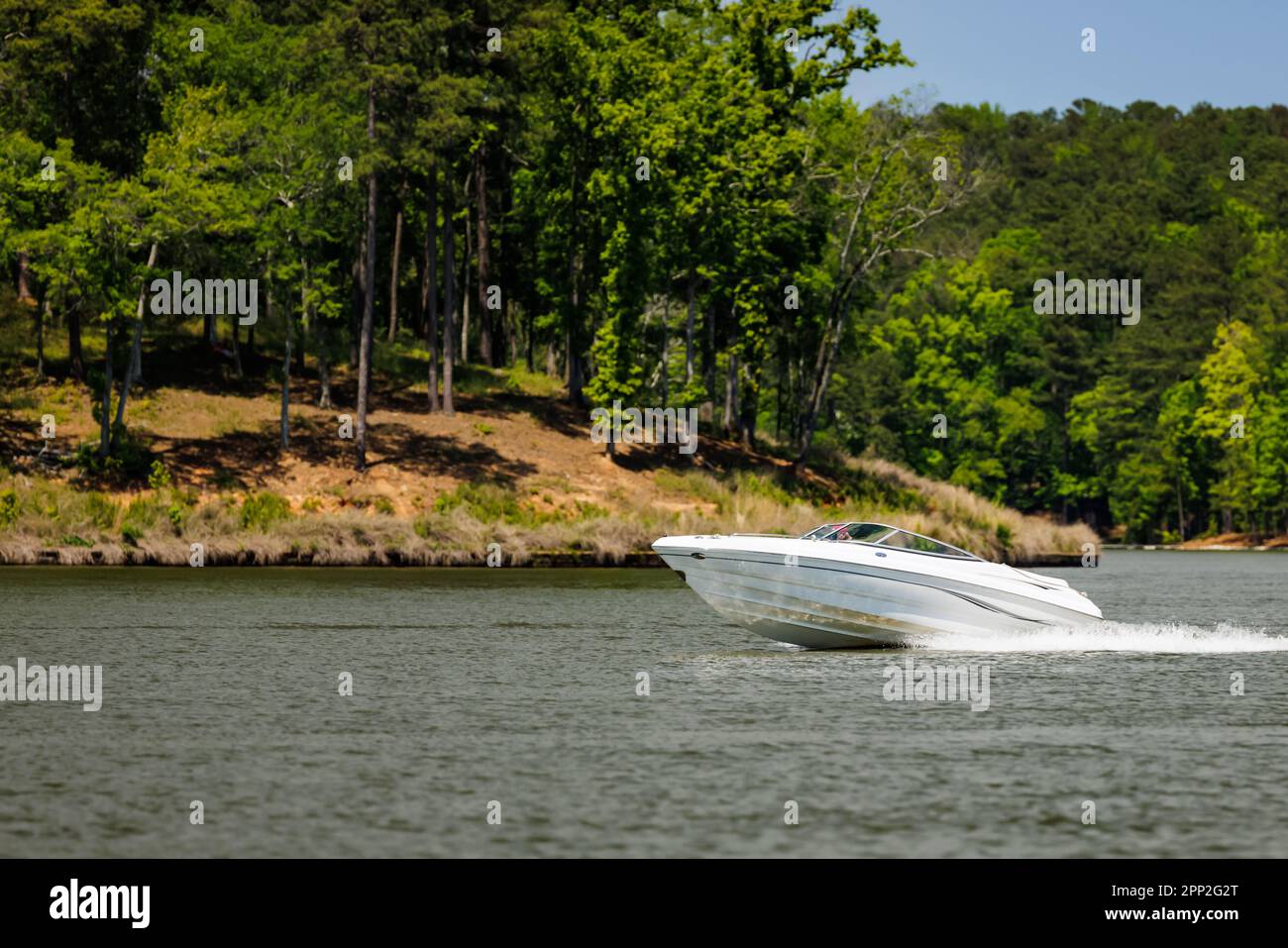 Boater on power boat enjoying summer day on Lake. Power boat cruising on freshwater lake. Stock Photo