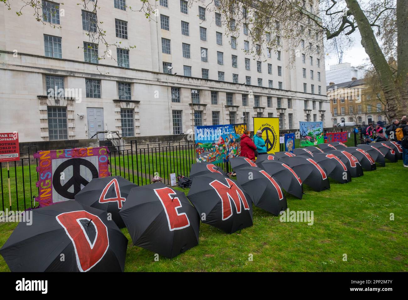 London, UK. 21 Apr 2023. Umbrellas spell out 'DEMILITARISE 4 SECURITY' in front of banners at the Defence Ministry. Many thousands came to Westminster to take part in the first of 4 days of Extinction Rebellion's protest demanding the government reverse policies that are fuelling climate change with new coal mines and oil fields and encouraging aviation. The protesters say their corruption has wrecked the economy, education system and our NHS, increased fuel costs and cut living standards while they blame poor families, people of colour, and new immigrants. Peter Marshall/Alamy Live News Stock Photo