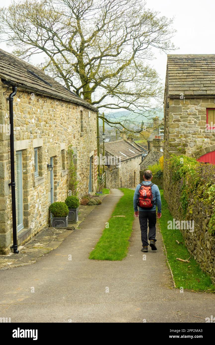 Man backpacking walking through a gate into the plague village of Eyam in the English Peak District countryside Derbyshire Stock Photo