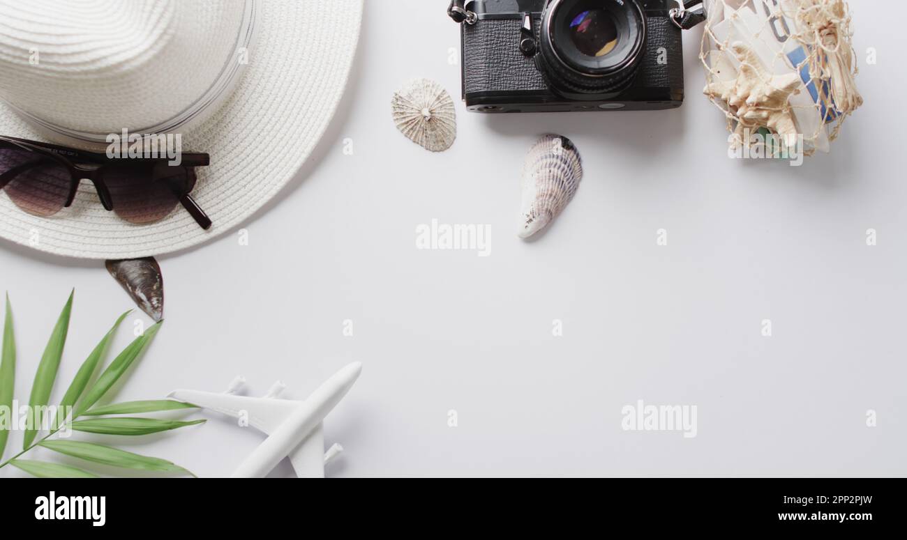 Close up of hat, sunglasses, camera, seashells and plane model on white