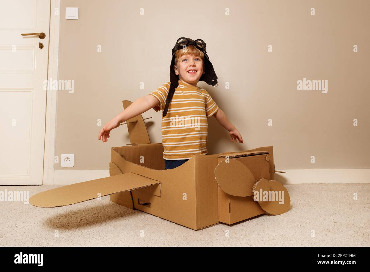 Boy play cardboard plane, wears hat, glasses pretends to fly Stock Photo Alamy