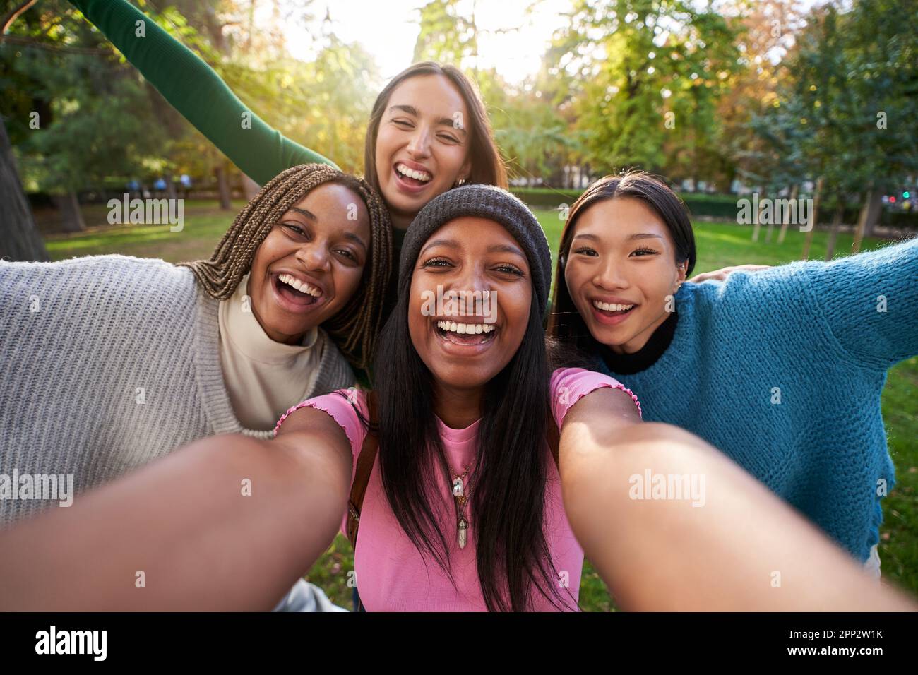 Group girls having fun outdoors taking selfie. Four smiling young women posing happily in the park.  Stock Photo