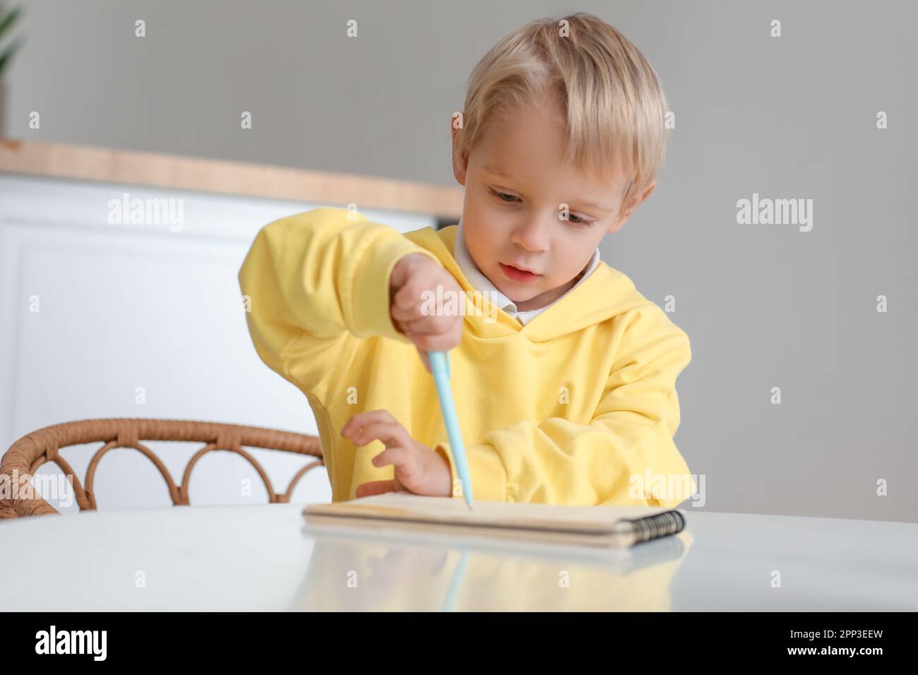 Cute little boy drawing in notebook at dining table Stock Photo - Alamy
