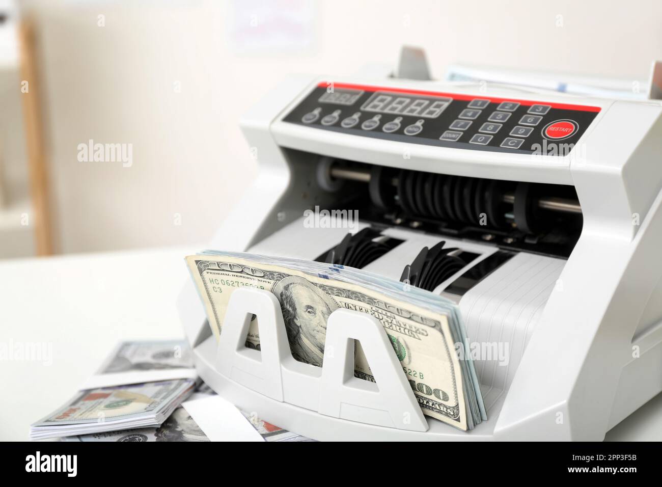 Modern cash counting machine with dollar banknotes on table in office ...