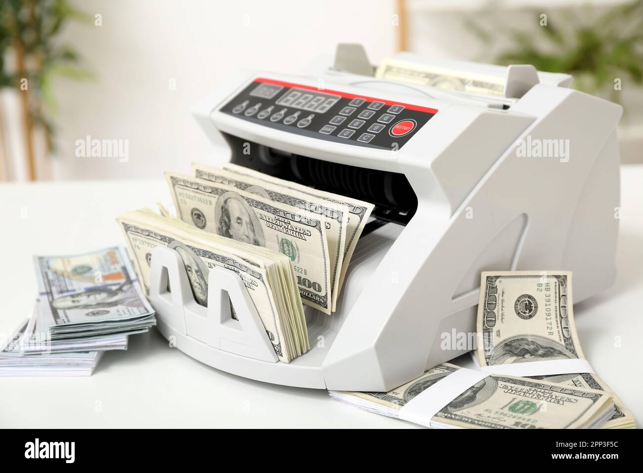 Modern cash counting machine with dollar banknotes on table in office ...