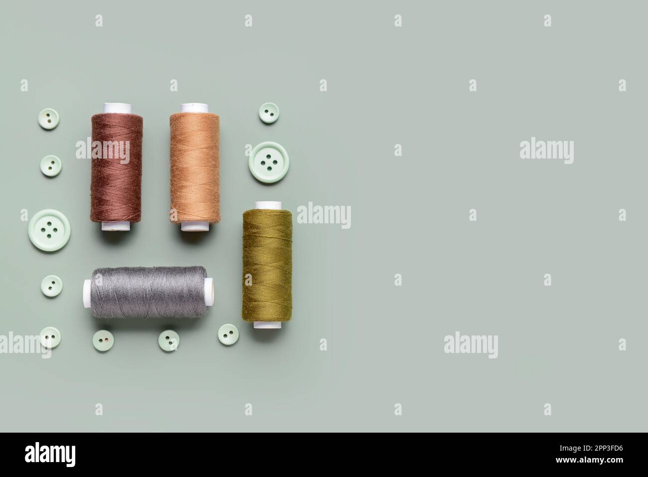 Composition with thread spools and buttons on grey background Stock Photo