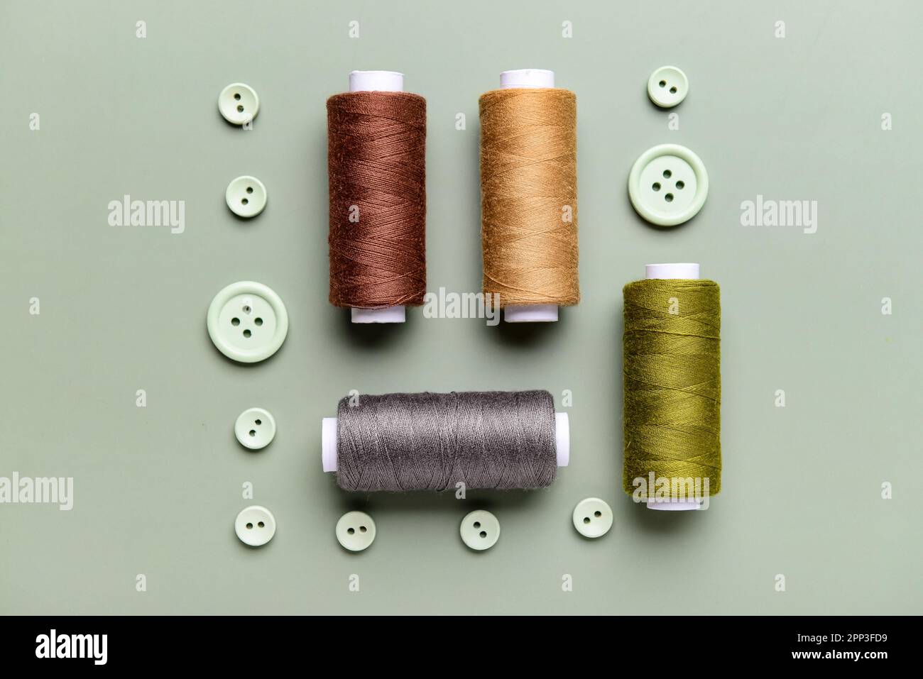Composition with thread spools and buttons on grey background Stock Photo