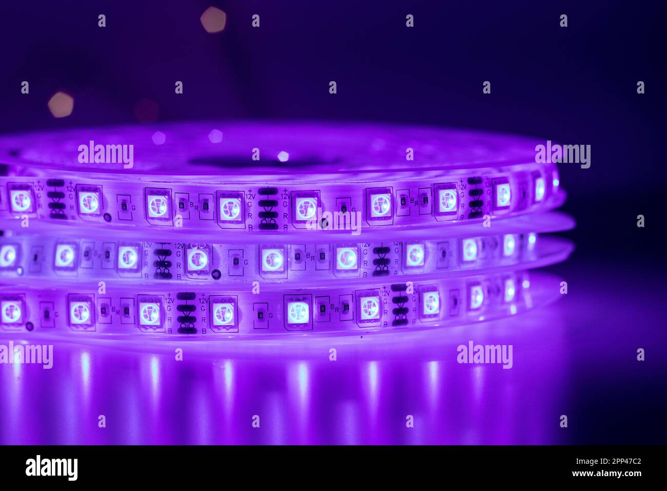 Roll of LED strip with bright neon purple lamps placed on table in dark