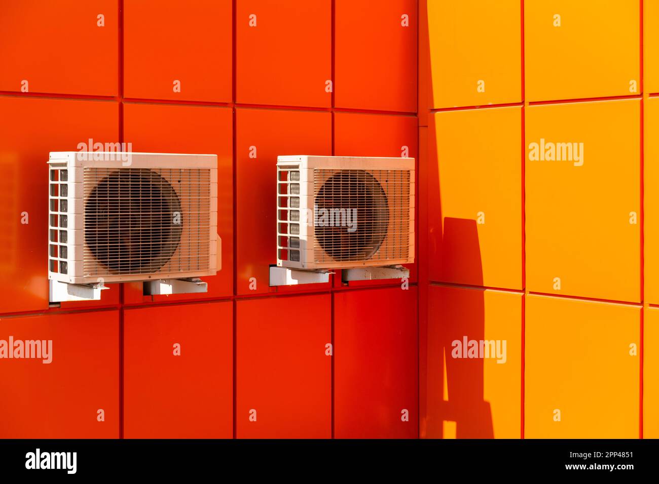 Two air compressors installation on orange wall outside. Air condenser