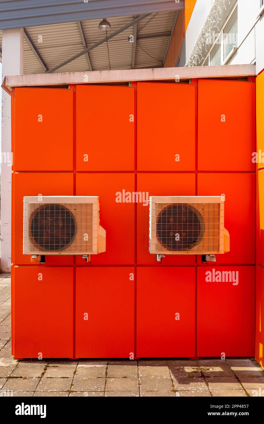 Two air compressors installation on orange wall outside. Air condenser outdoor unit for heat