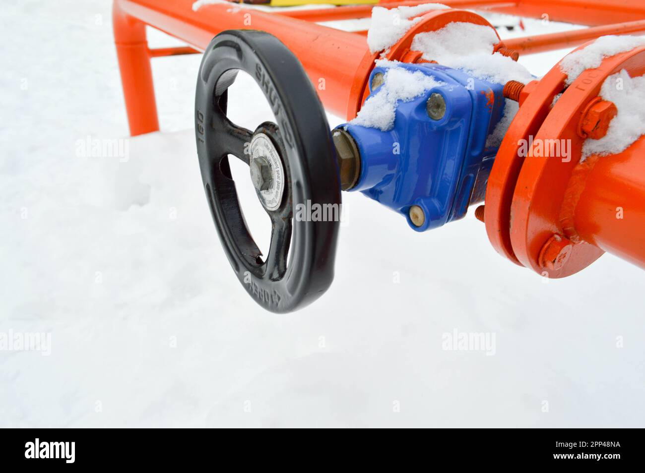 Industrial shut-off regulating protective pipe fittings. Black valve for opening, closing on an iron orange metal pipe with flanges, studs, nuts again Stock Photo