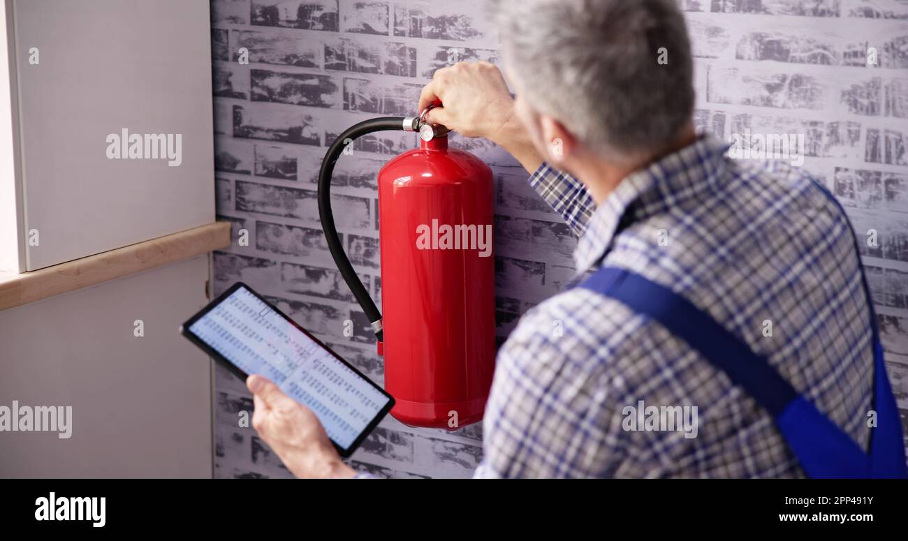 Worker Installing Fire Extinguisher. Inspection Service. Checking