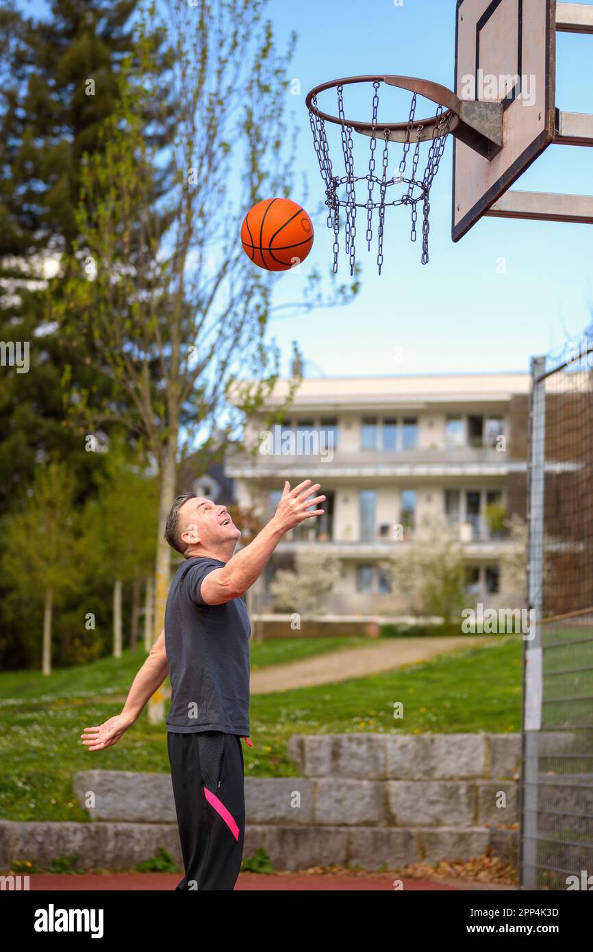 Middle age man in black sports shorts throwing the basketball up on a sports field Stock Photo