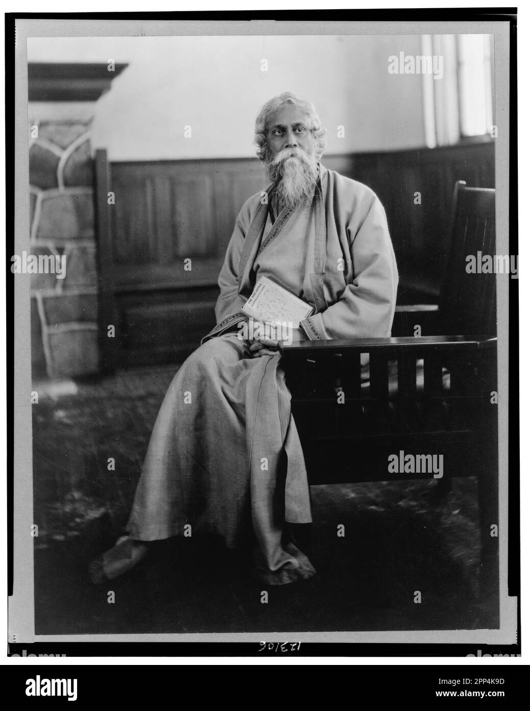 Rabindranath Tagore, full-length portrait, seated, facing front. Circa 1916.   Tagore is (almost certainly) holding a copy of The Post Office, 1914 Ma Stock Photo